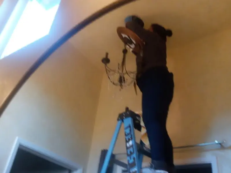 Electrician installing a chandelier in a Sealy residence